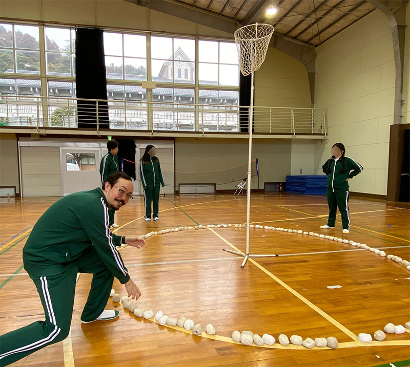 Man picking up balls to throw into the basket